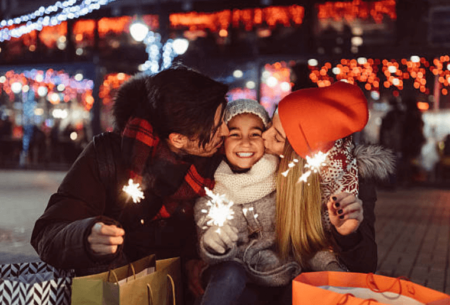 parents kissing child in a wintery scene - how to plan a winter family vacation on a budget